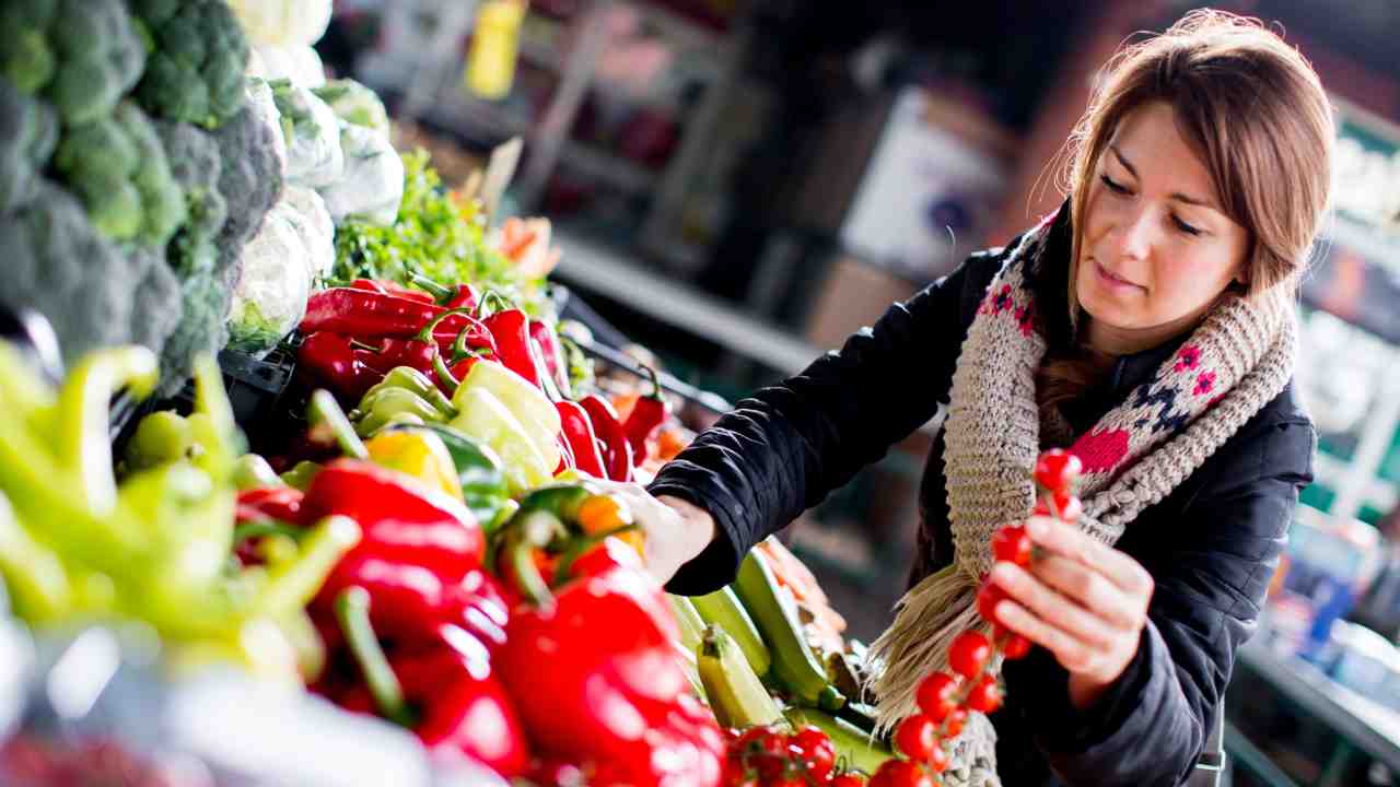Donna che fa la spesa scegliendo attentamente la verdura da comprare 