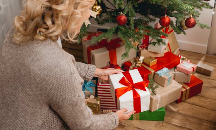 Donna che mette i regali sotto l'albero di Natale