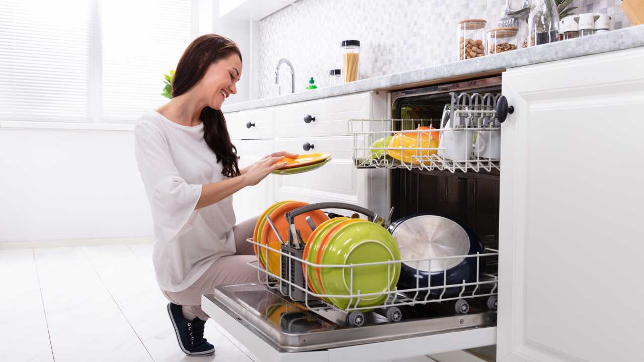 Donna che sistema i piatti in lavastoviglie prima dell'uso