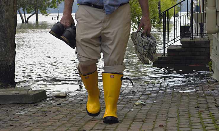 Uomo che cerca di recuperare scarpe dopo un'alluvione