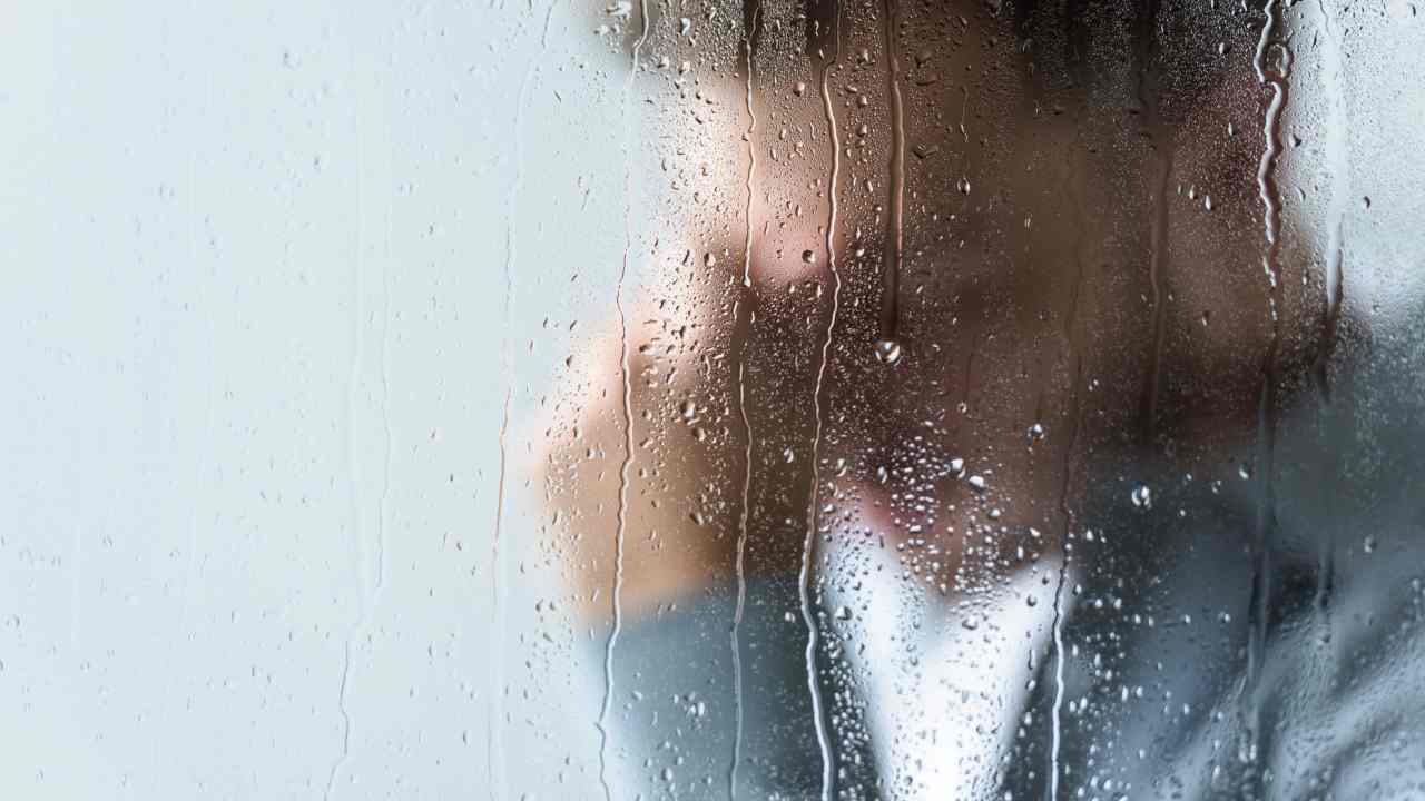 Uomo pensieroso dinanzi ad un vetro bagnato dalla pioggia