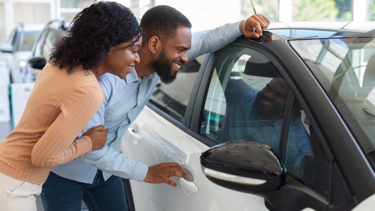 Giovane coppia in concessionaria che valuta l'automobile da acquistare
